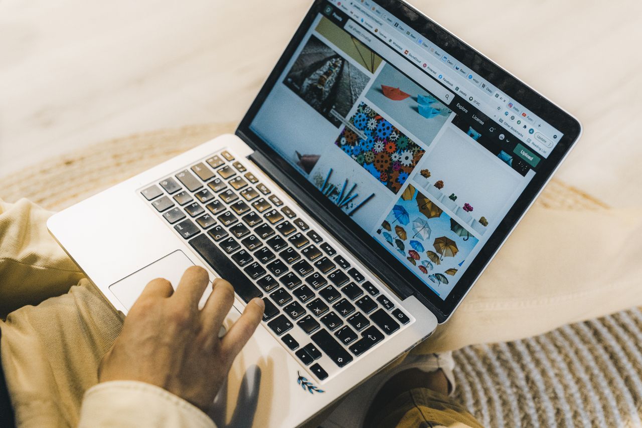 Une personne utilisant un ordinateur portable pour naviguer sur des sites de photos de stock. Travail en freelance dans un cadre chaleureux.